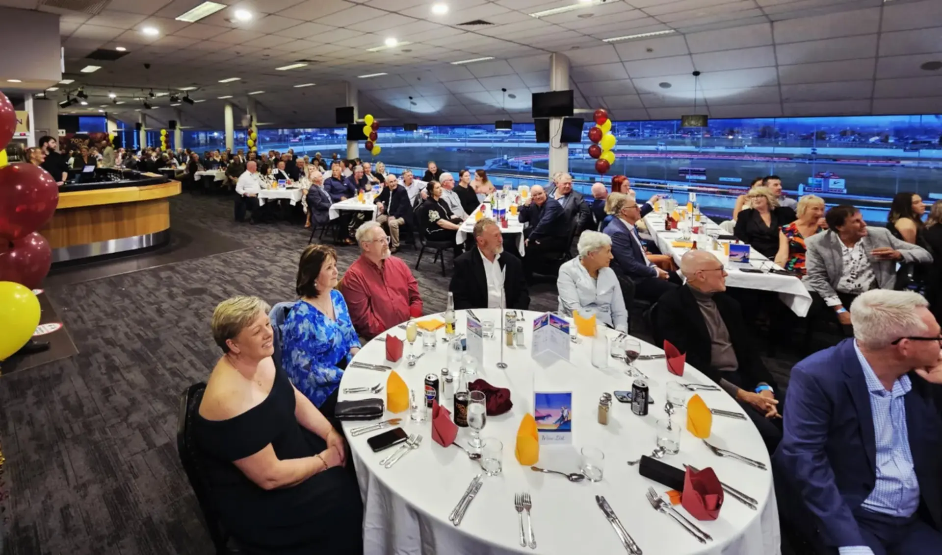 Crowded dining event with guests enjoying dinner.
