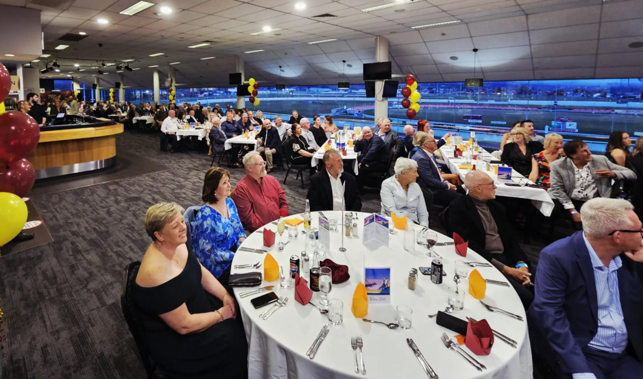 Crowded dining event with guests enjoying dinner.